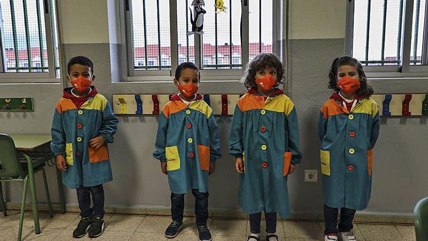 A la izquierda, los niños esperan en fila y a distancia para entrar en el colegio. A la derecha, los pequeños de uno de los grupos burbuja, con el mismo color de mascarilla. | Nico Rodríguez