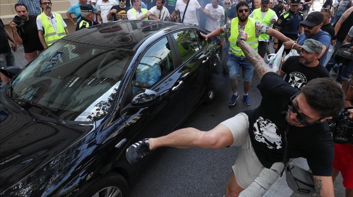 Un participante en la manifestación de taxistas da una patada a un cabify. Un participante en la manifestación de taxistas da una patada a un cabify.