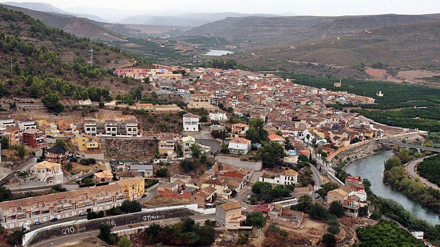 Una perspectiva del núcleo urbano de Sumacàrcer, con el cauce del Xúquer a sus pies y la presa de Tous al fondo.