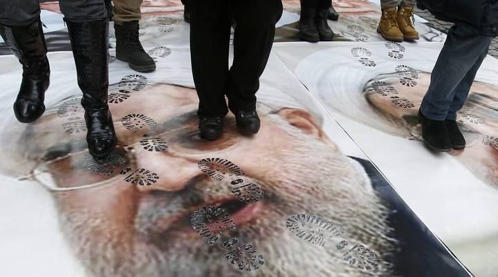 People walk over a portrait of Iran's President Hassan Rouhani as they take part in a protest against his visit to France in central Paris