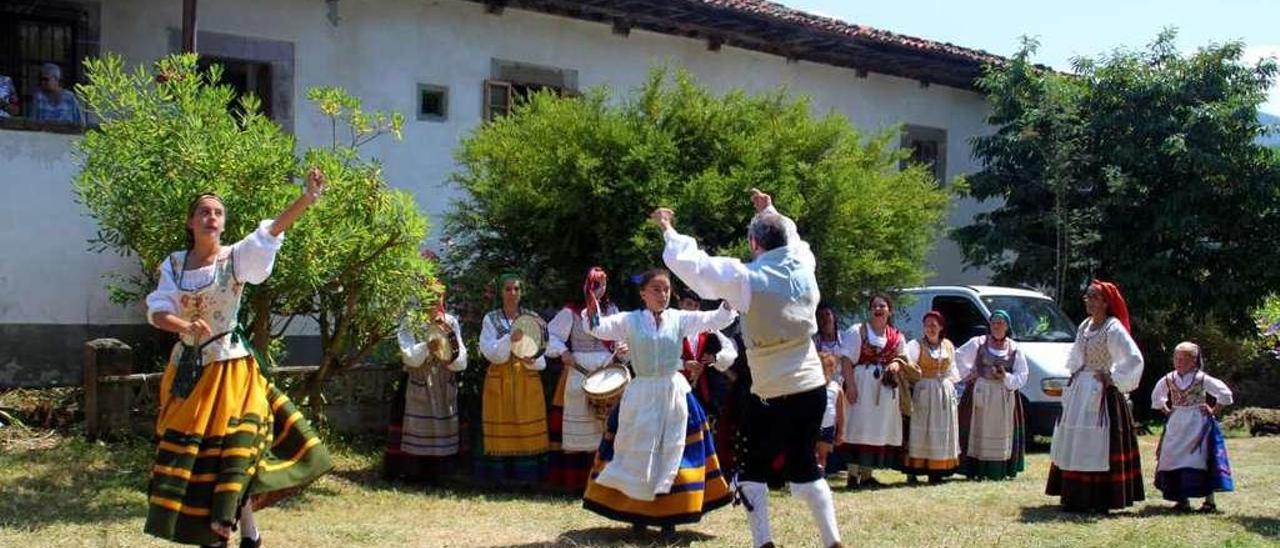 Una representación de la Agrupación Folclórica &quot;Picos de Europa&quot; baila delante de la casona de La Trapiella, en Areñes.