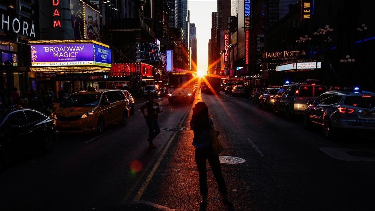 Gente tomando fotografías de la puesta de sol sobre Manhattan alineada exactamente con las calles, es un fenómeno conocido como Manhattanhenge en Times Square en la ciudad de Nueva York.