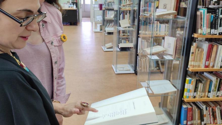 La bibliotecaria Manuela Busto, en el centro de Castropol, con uno de los libros de la exposición «100 años de firmas», englobado en la celebración del centenario. | Tania Cascudo