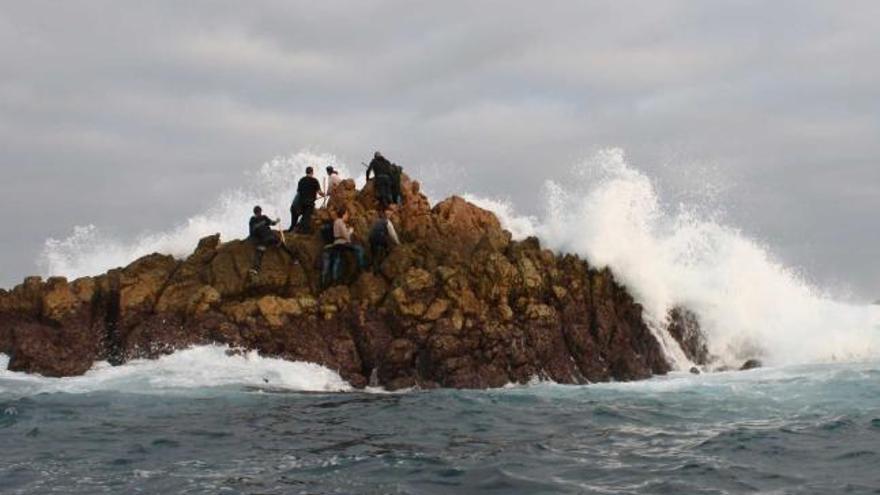 Pescadores, en una de las rocas del entorno del Cabo Peñas ante un fuerte oleaje.