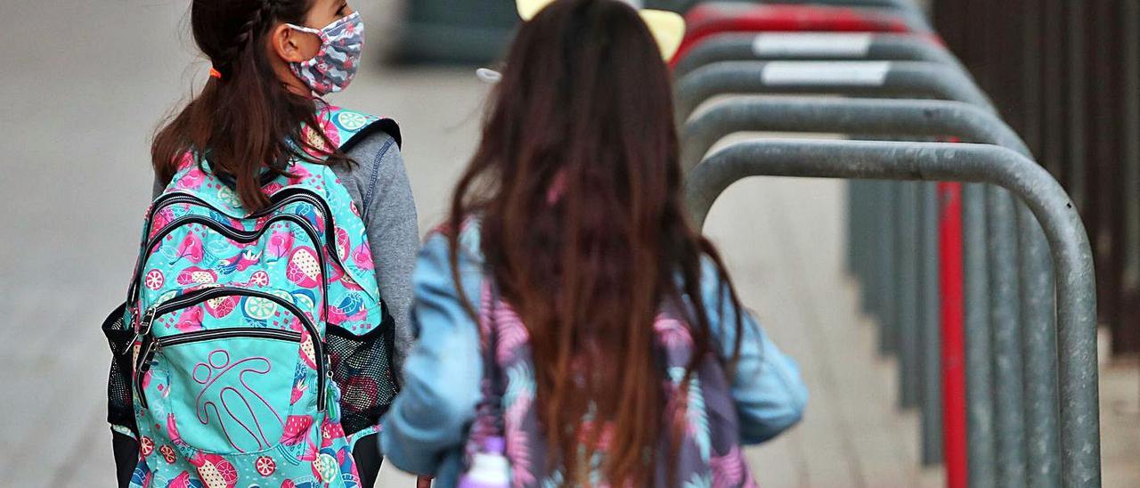 Dos alumnas se dirigen al colegio, con mascarilla y sus mochilas, en València.