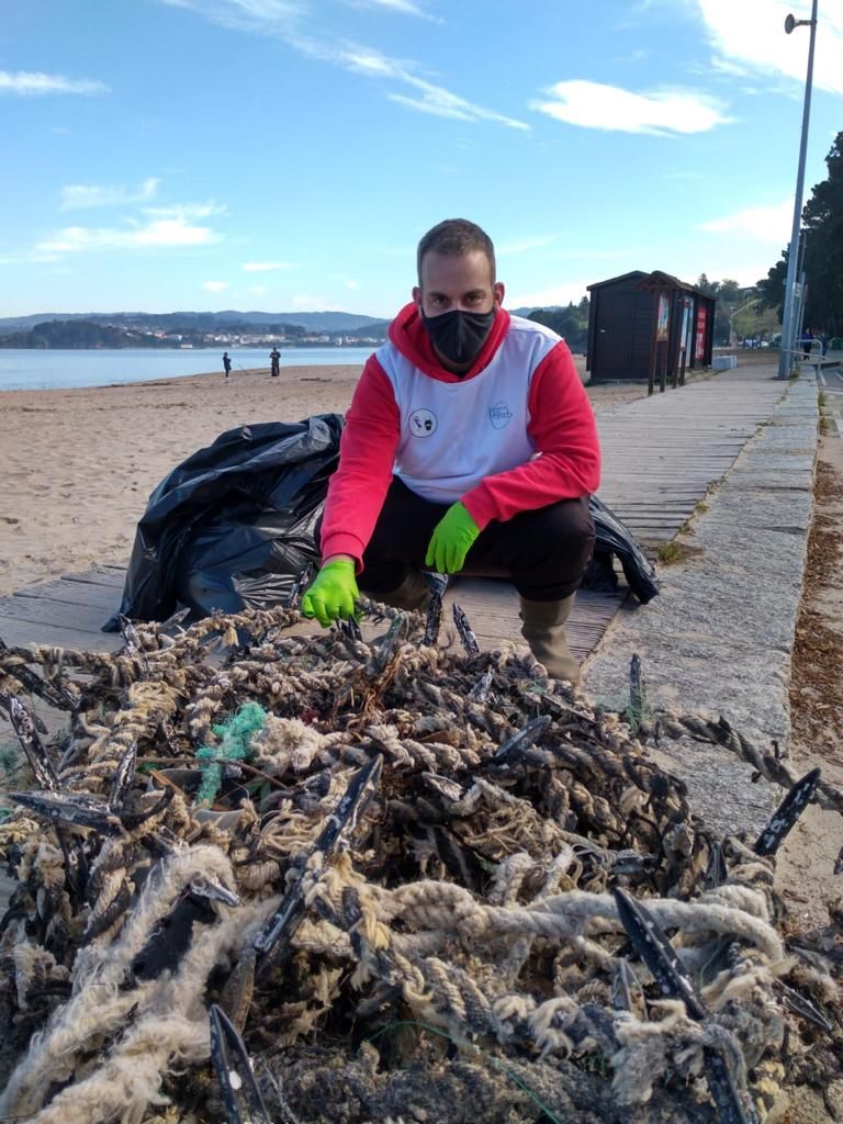 Uno de los voluntarios muestra restos de redes y aparejos retirados del arenal