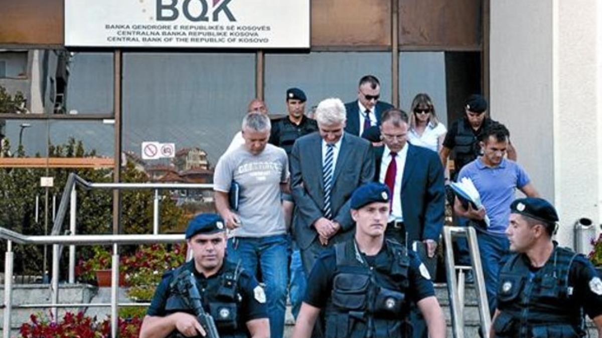 Policías kosovares se llevan detenido a Hashim Rexhepi (detrás, en el centro), gobernador del Banco Central, el viernes, en Pristina.