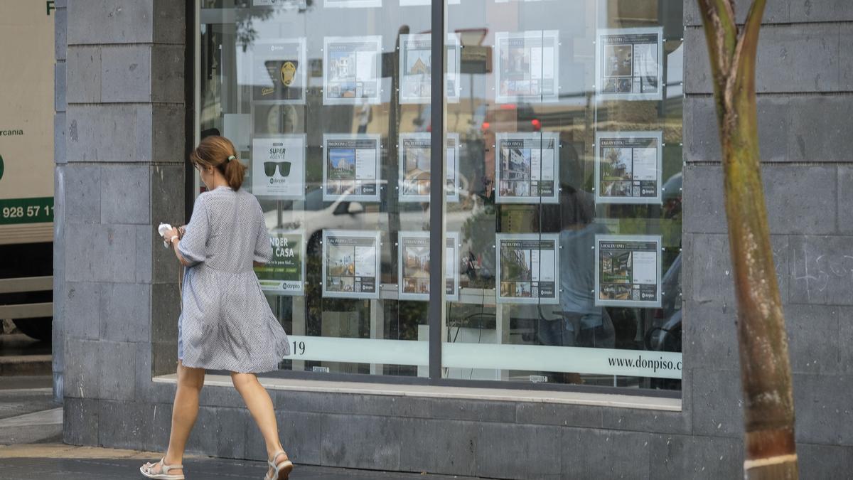 Una mujer pasa frente al local de una inmobiliaria.