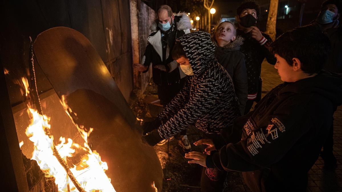 Vecinos de Sant Roc se calientan con una hoguera en la calle en enero del año pasado, en un momento álgido de los cortes de luz en este barrio de Badalona.