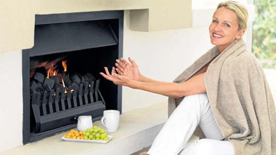 Una mujer disfruta del calor de una chimenea.