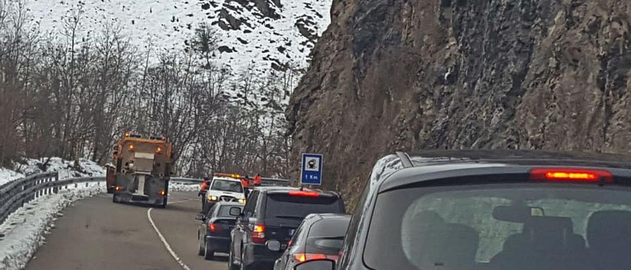 El tráfico detenido junto al embalse de Rioseco, con operarios de Carreteras limpiando un argayo al fondo. | L. M. D.