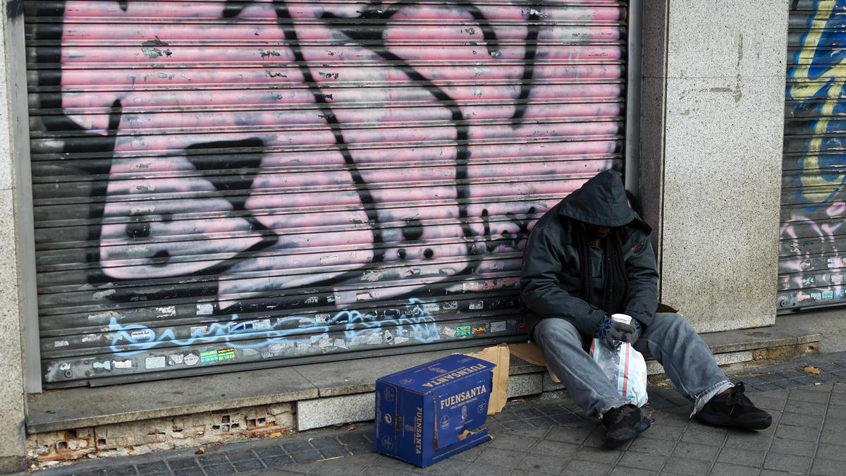 Un hombre sin hogar pide limosna en la calle.