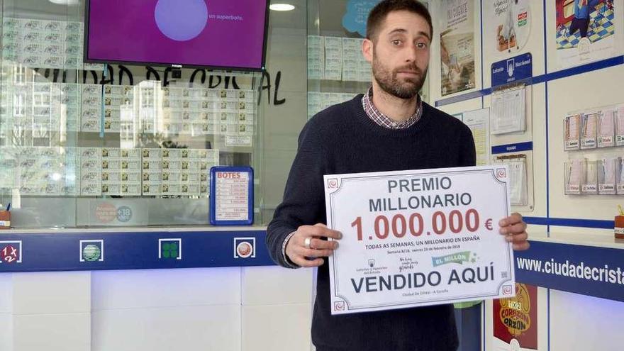 Pedro González posa, ayer, con el cartel del premio de un millón de euros.