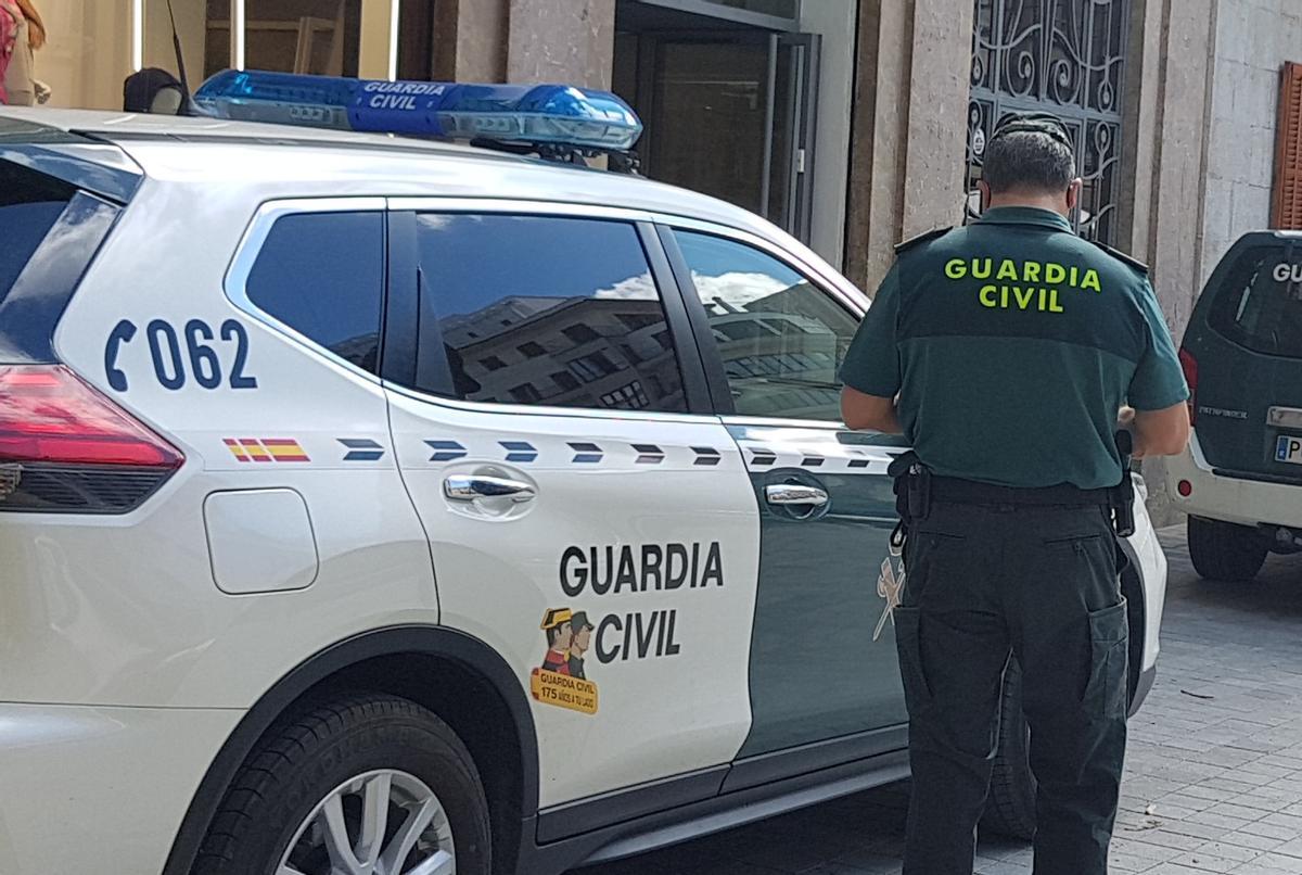 Un agente de la Guardia Civil junto a su coche patrulla.