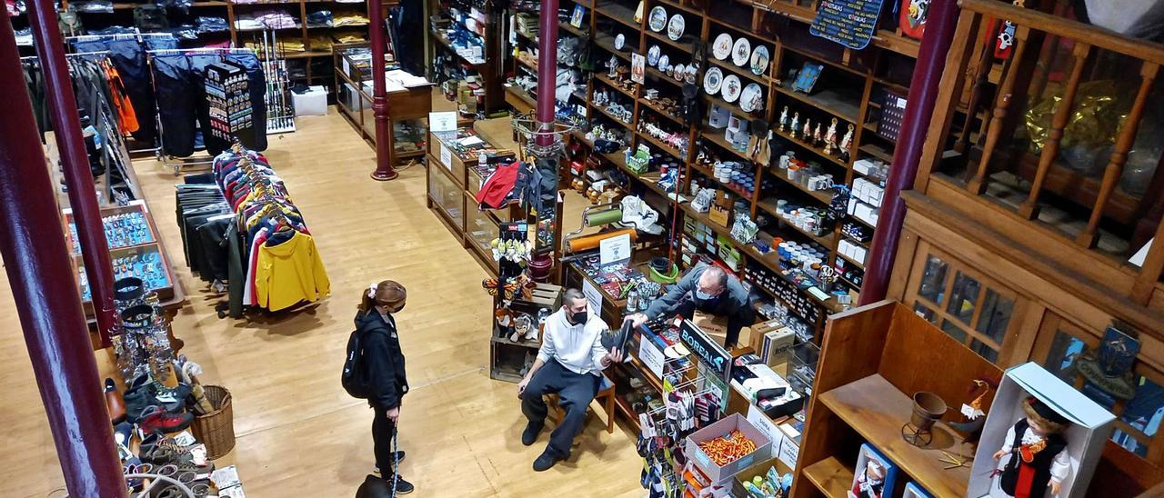 Guillermo Rodríguez, a la puerta del comercio. Debajo, a la izquierda, vista del local en la calle Covadonga. En el centro, cuando estaba ubicado en la calle San Pelayo. A la derecha, imagen actual del exterior. | María Villoria