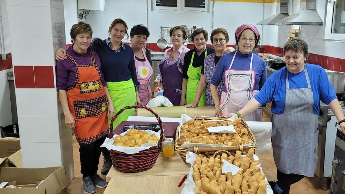 : Integrantes de la asociación de mujeres “So la Malena” preparan algunos de los productos que se degustarán en el mercado rural de otoño. En el centro, tercera y cuarta por la izquierda, Marigel García y Duli Fernández, ganadoras del “Concurso Mundial de casadielles”.