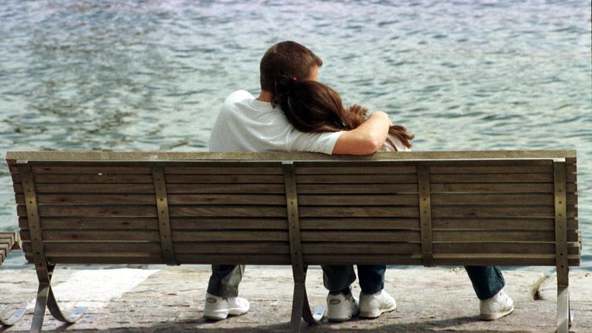 Una pareja abrazada en un banco.