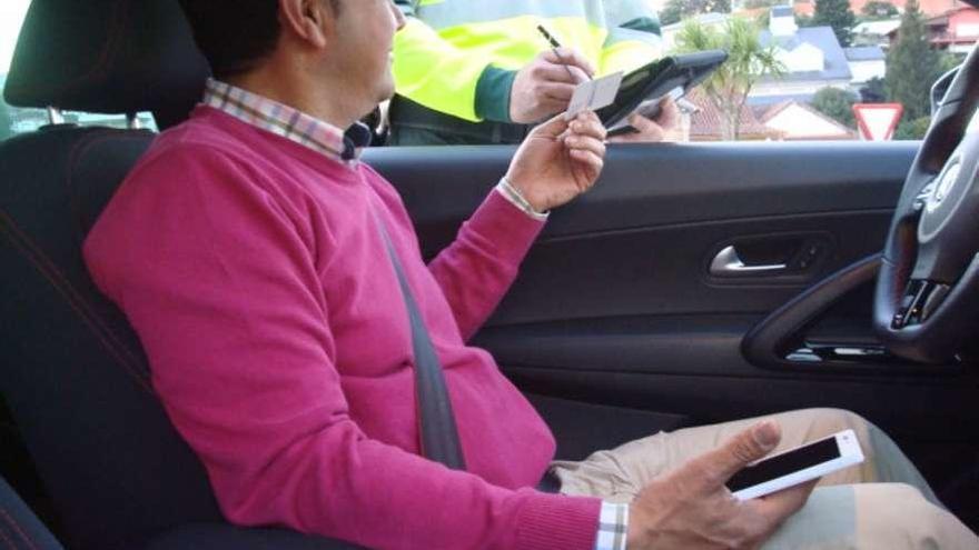 Un agente sanciona a un conductor tras ser interceptado con el móvil.
