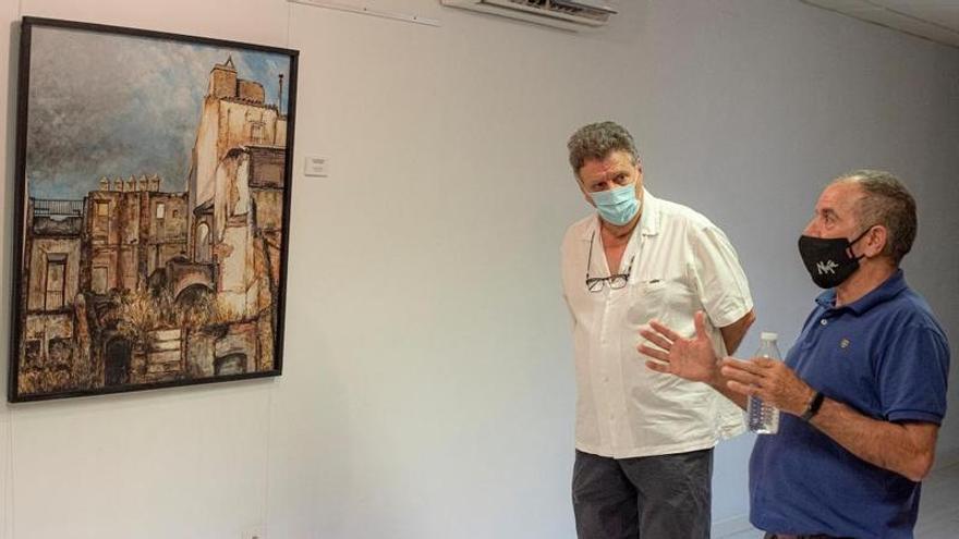 Miguel Ángel Ruiz mira a Noja mientras explica uno de los cuadros de la primera exposición de la asociación centrado en la capital pacense.