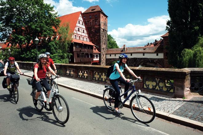 Ciclistas cruzando el puente Maxbrücke de Núremberg, Franconia, Alemania