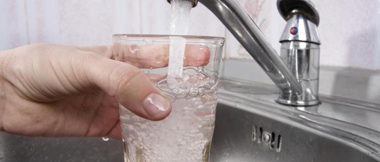 Una usuaria llena un vaso de agua en el fregadero.