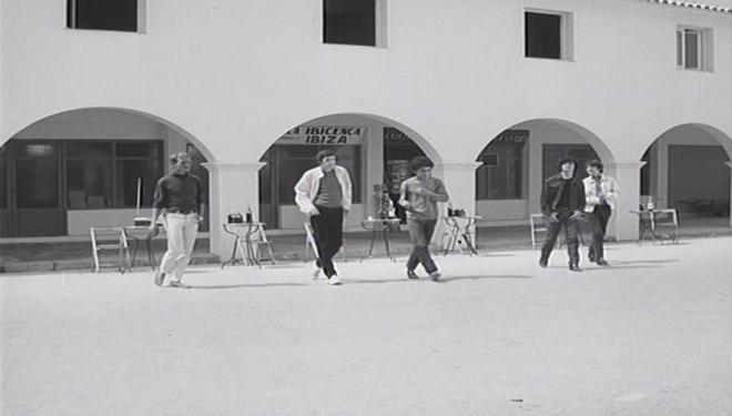 Un grup de moderns es dirigeixen al protagonista i el seu piano en arribar al port d'Eivissa.