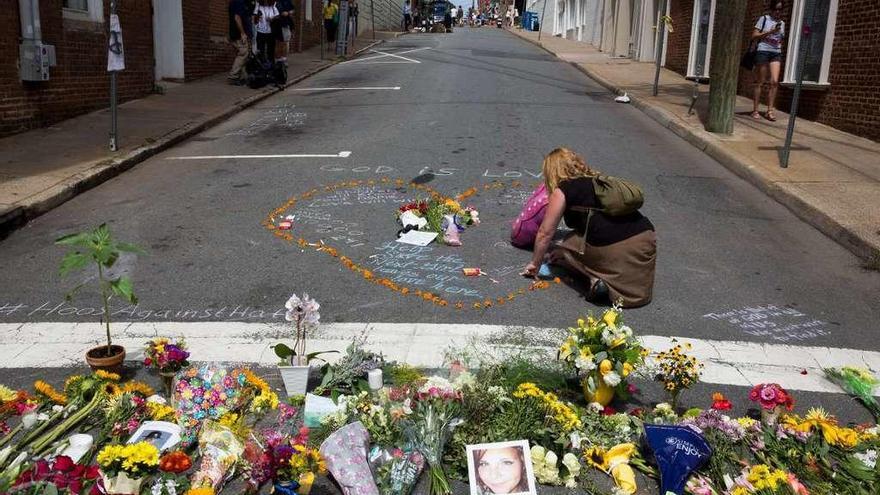 Una mujer coloca flores en el lugar donde una mujer murió atropellada por un supremacista. // Efe