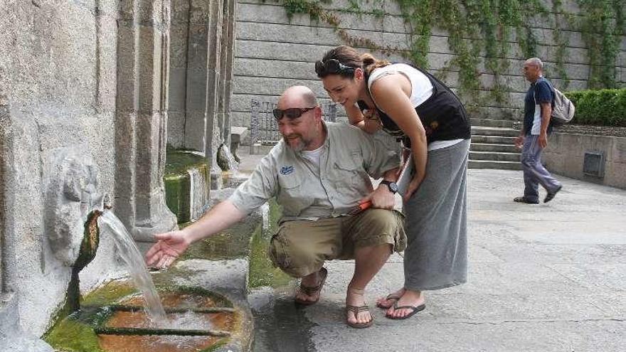 Unos turistas prueban el agua de As Burgas // I.Osorio