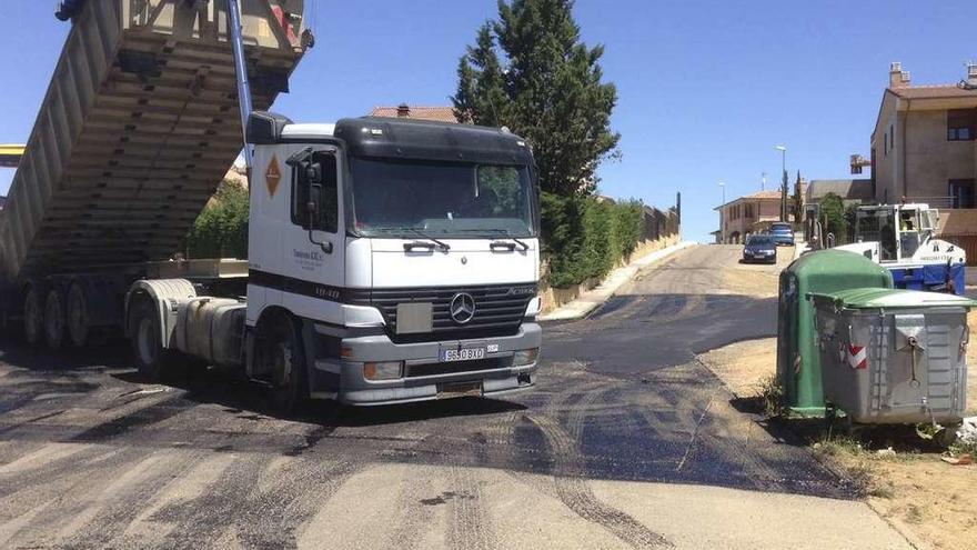 Un camión vierte grava en la rotonda tras echar una capa bituminosa en las calles Catalanas y Zafra el 20 de mayo de 2015.
