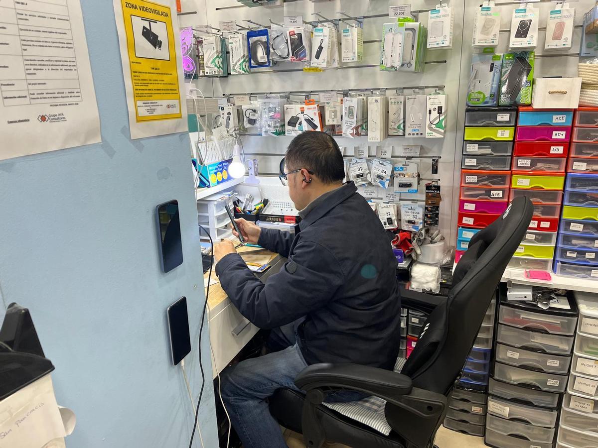 Yan Qiu repara un teléfono en su tienda.