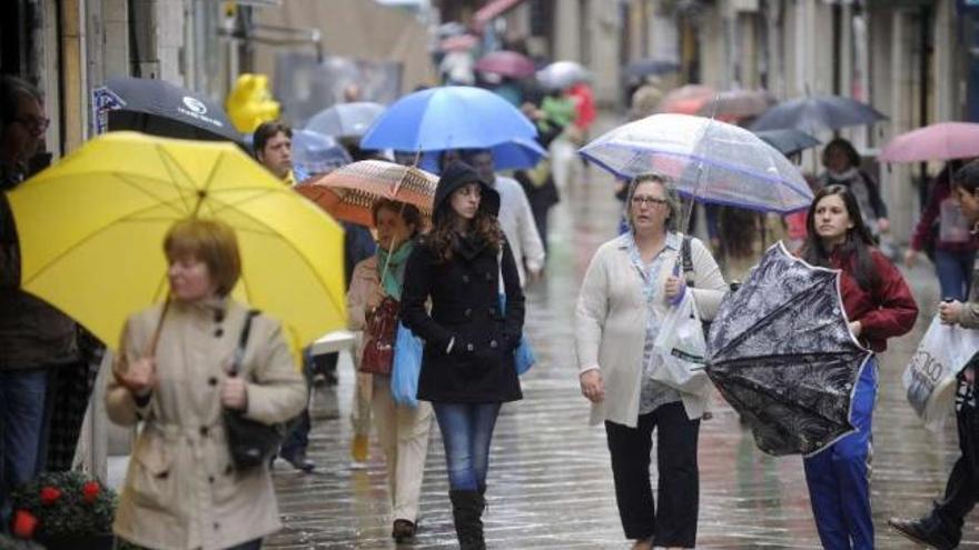 Un grupo de gente pasea por A Coruña en una jornada de lluvia de la pasada primavera. / juan varela