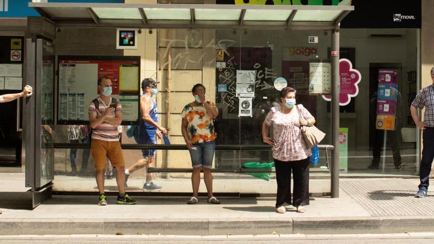 Varias personas en una parada de autobús.