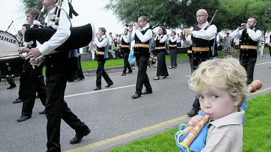 Un niño toca una pequeña gaita de juguete, al paso de una de las bandas. / juan plaza