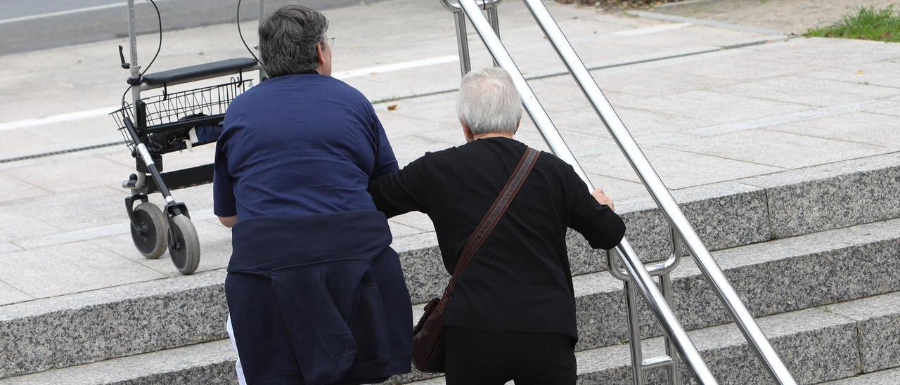 Una cuidadora ayuda a una mujer dependiente.