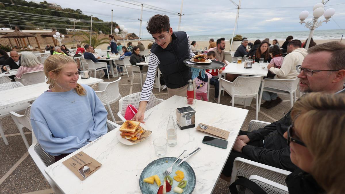 Un camarero sirve unas mesas en la terraza de una cafetería de Benicàssim.