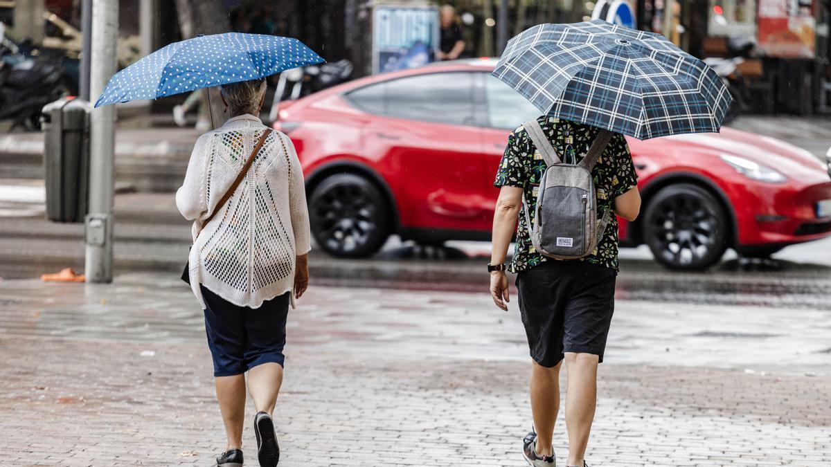Dos personas caminan bajo la lluvia.