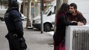 Dos okupes conversen davant la mirada d’un agent, avui, a Barcelona.
