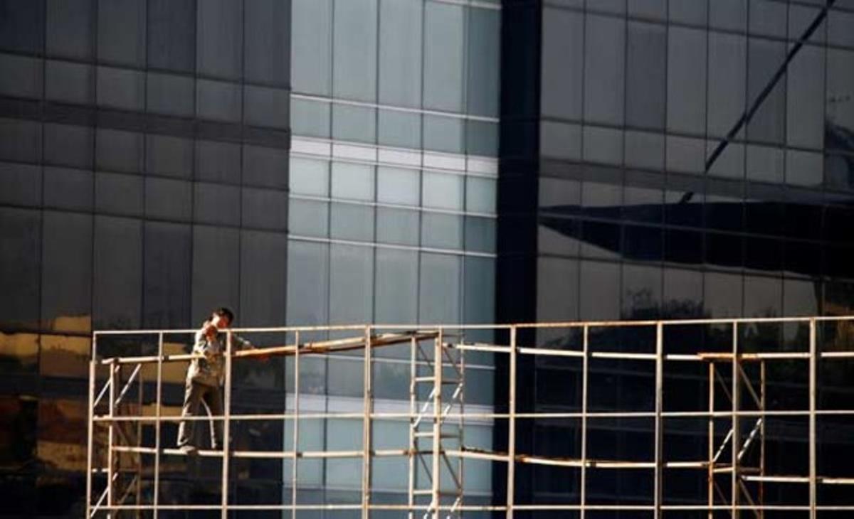 Un operario trabaja en unos andamios frente a un nuevo edificio residencial en Beijing. China ha anunciado una batería de medidas para enfriar el candente mercado inmobiliario.