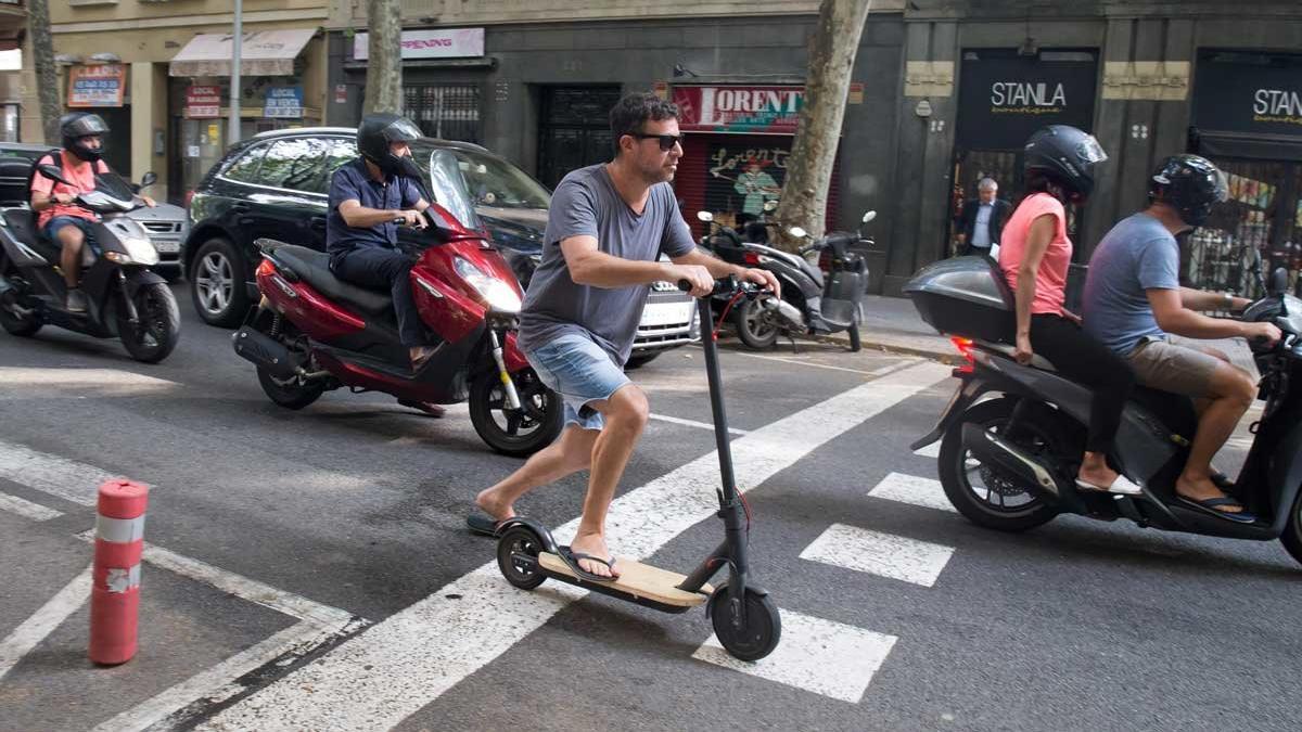 Un hombre conduce un patinete eléctrico por la calzada