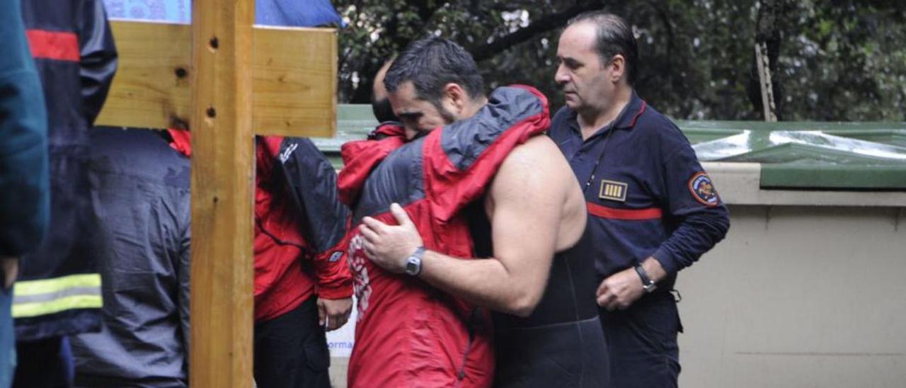 Bomberos se abrazan tras la muerte de un compañero.