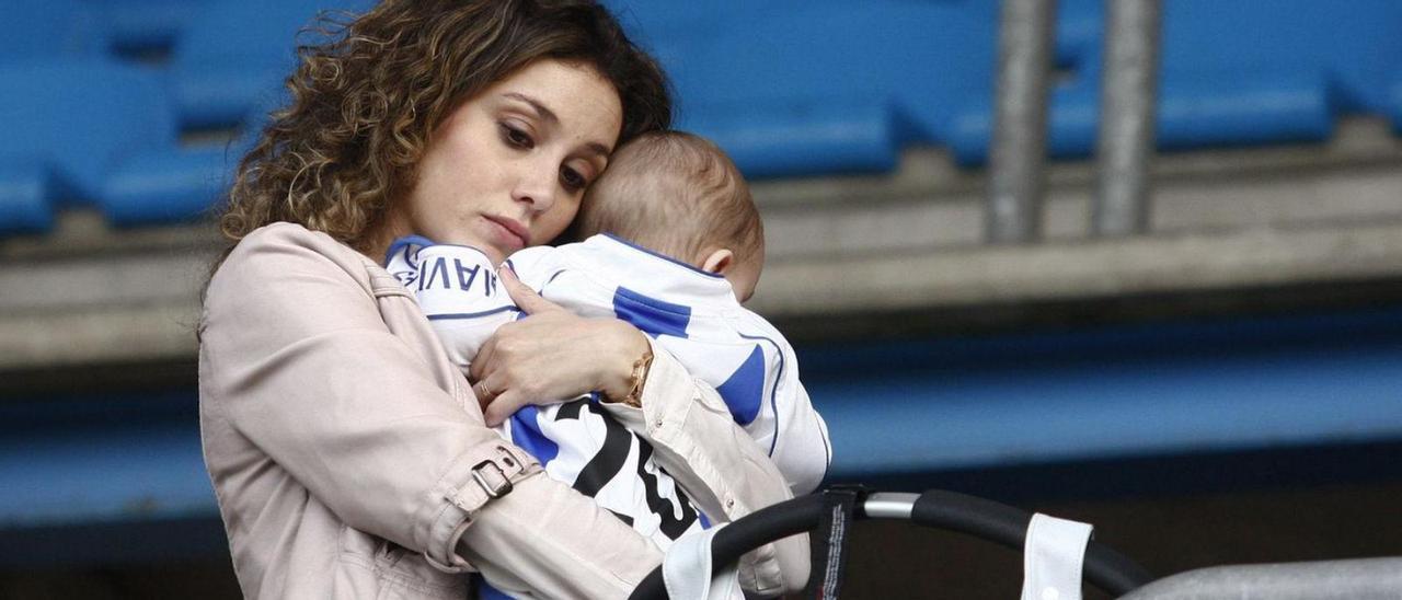 Una mujer abraza a un bebé vestido con la camiseta del Real Avilés en una grada del estadio Suárez Puerta. | Miki López