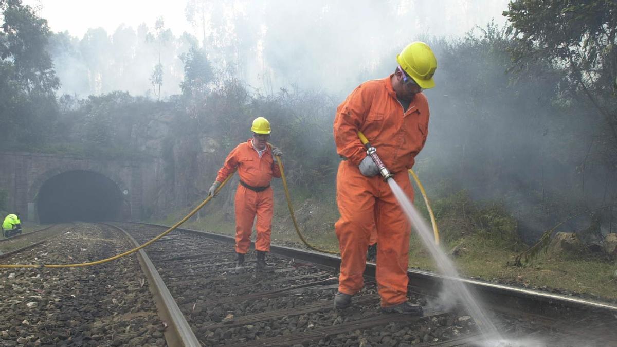 Operarios refrescan un tramo de vía durante un incendio