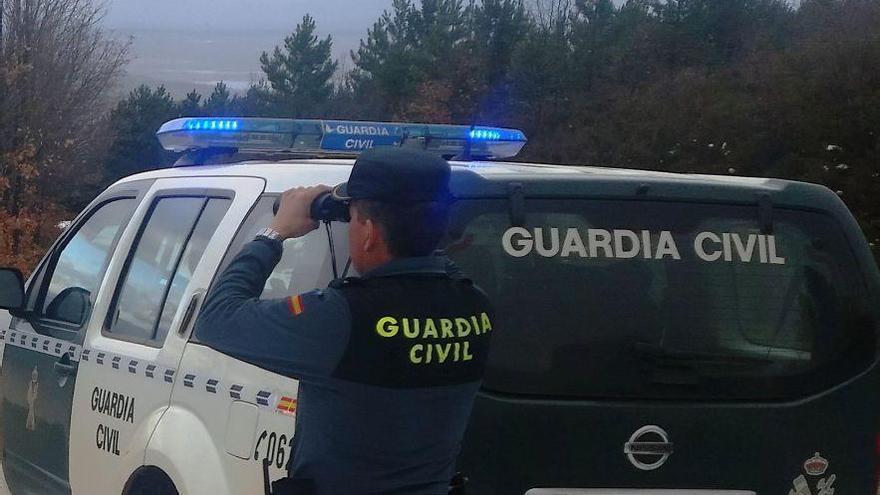 Un Guardia Civil observa una zona mirando con unos prismáticos