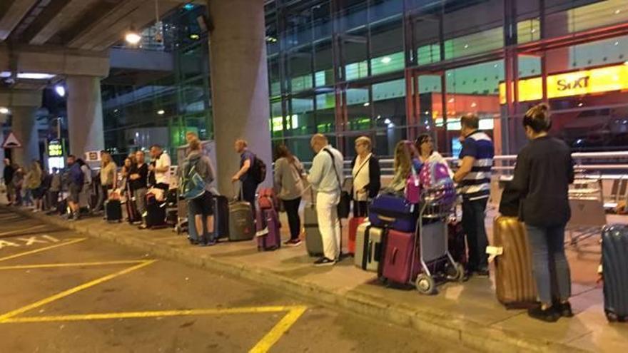 Pasajeros esperando la llegada de un taxi en la parada del aeropuerto al filo de la una de la madrugada del pasado domingo.