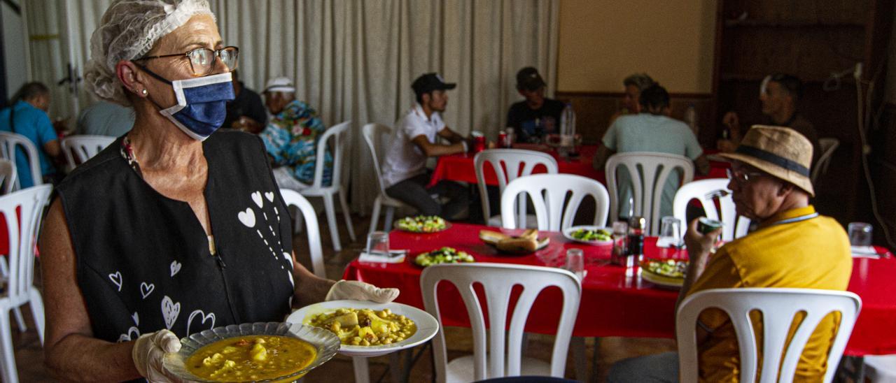 Una de las 15 personas que atiende el comedor sirve platos de comida