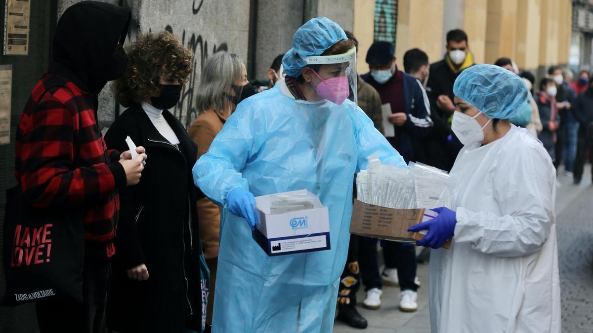 Dos sanitarias recogen test de Covid-19 de las personas que hacen cola en el Centro de Salud Universidad, en Madrid.