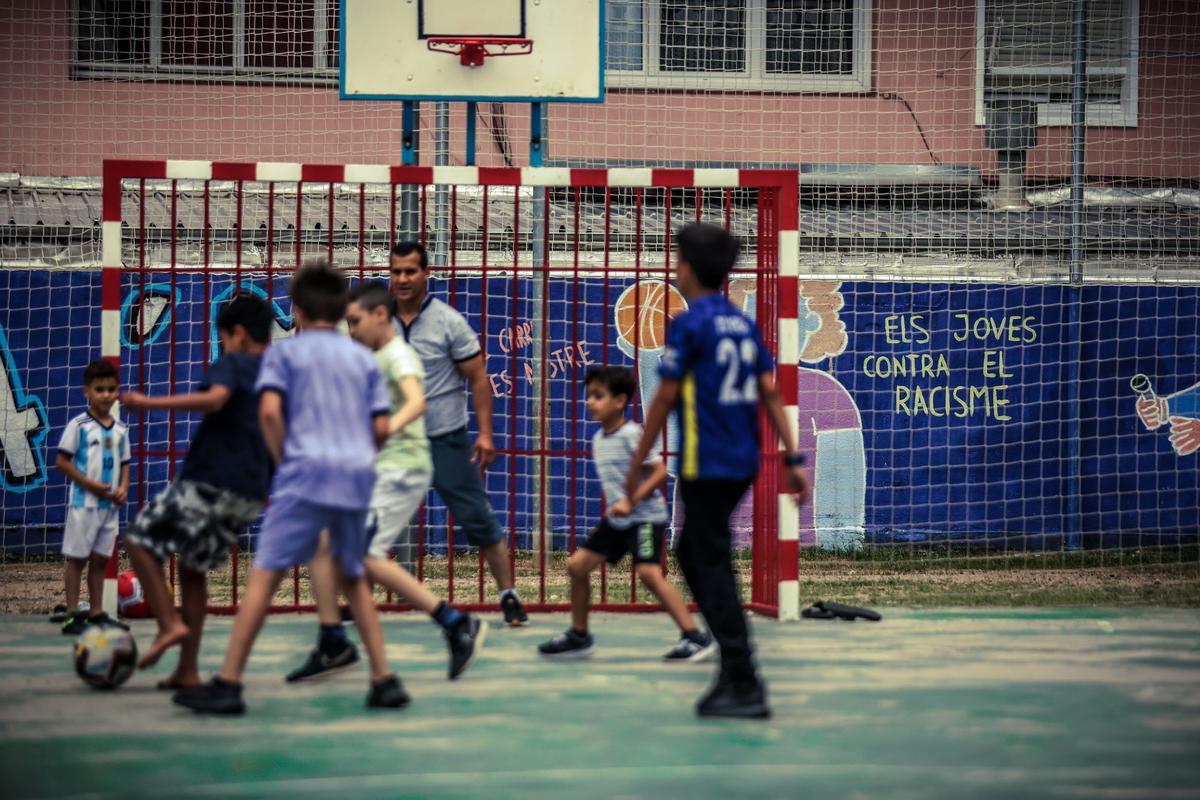 Uno grupo de niños de familias de orígen migrante juegan a fútbol en una plaza de Ripoll.