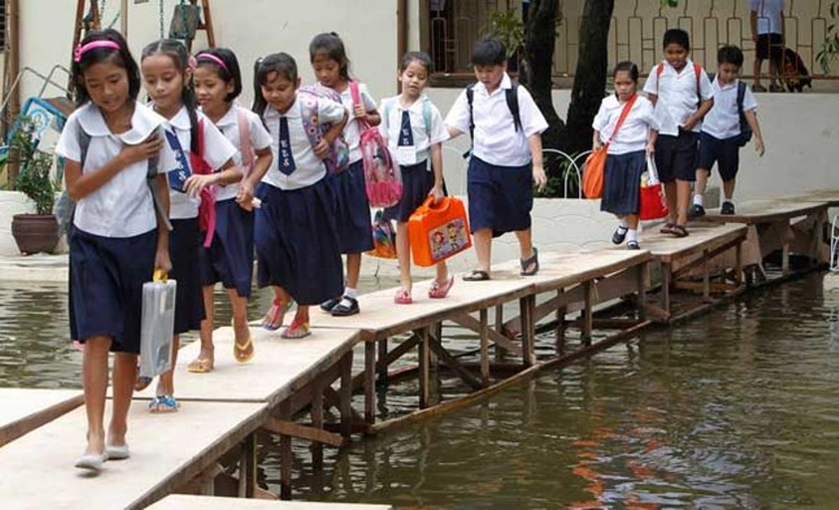 Nens en edat escolar travessen una zona inundada pel tifó Sepat en un improvisat pont de taules de fusta mentre es dirigeixen a les seves classes a l’escola primària Coloong a la ciutat de Valenzuela, al nord de Manila.