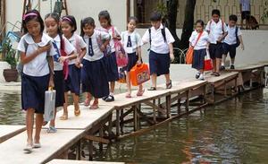 Nens en edat escolar travessen una zona inundada pel tifó Sepat en un improvisat pont de taules de fusta mentre es dirigeixen a les seves classes a l’escola primària Coloong a la ciutat de Valenzuela, al nord de Manila.