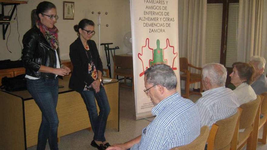 Las dos trabajadoras de la asociación escuchan las dudas de los asistentes a la conferencia.